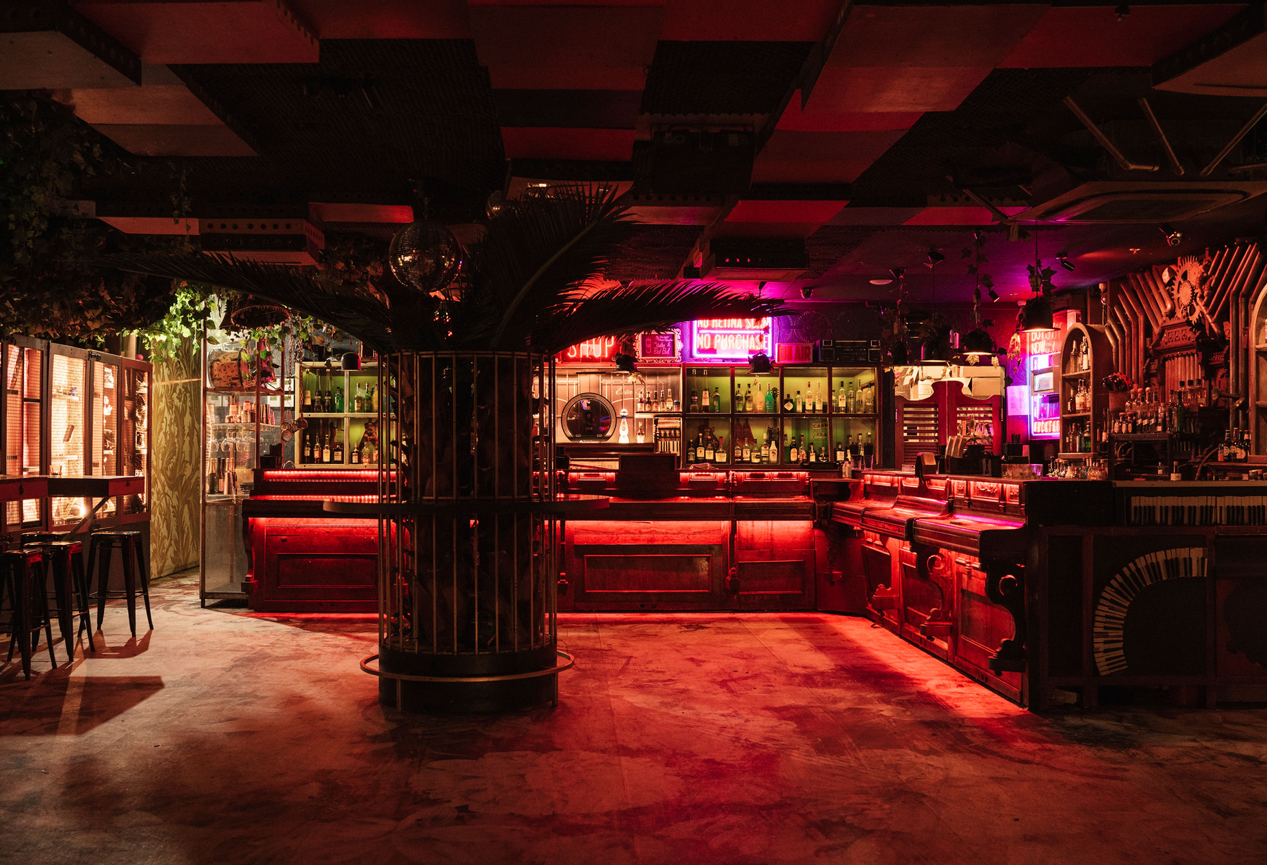 Pawn and Co's current interior glowing red with its white piano installation visible beside the bar